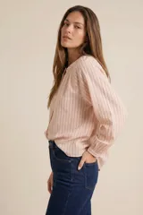 Blusa de corte oversize con estampado de rayas verticales, cuello redondo con pequeña abertura frontal abotonada y mangas largas con puños elásticos.