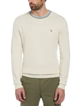Sweater Original Penguin de hombre en color beige, confeccionado en 100% algodón. Cuenta con cuello redondo con detalles de líneas en verde y azul, puños y dobladillo acanalados, y el clásico logo bordado del pingüino en el pecho.