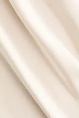 Pollera midi de tiro alto, color beige, confeccionada en tela satinada de caída suave con acabado brillante y leve vuelo en el bajo.