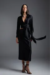 Vestido midi negro de satén con escote en V, corte cruzado con lazo en la cintura y mangas largas.