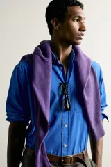 Camisa de corte relajado confeccionada en tejido de algodón de color azul, con cuello abotonado, manga larga, bolsillo frontal de parche y cierre de botones.