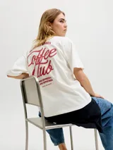 Remera blanca de manga corta, con corte holgado y diseño liso, cuenta con un pequeño estampado en el pecho con la leyenda "Coffee Club".