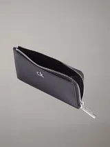 Billetera tipo tarjetero grande de color negro, con cierre en forma de L y logo metálico de la marca en el frente.