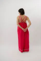 Mono enterito de lino color fucsia, con escote en V, tirantes dobles regulables, bolsillos laterales y detalles de costuras decorativas en contraste en el escote y los tobillos. Presenta una silueta amplia y relajada de pierna ancha.