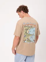 Remera oversize color beige de manga corta, con gran estampa colorida en la espalda con diseño de mapa de playa y la inscripción "Rusty County".