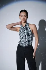 Top sin mangas, ajustado al cuerpo, con cuello halter y estampado de piel de serpiente en tonos blanco, negro y gris.