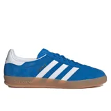Championes Adidas Gazelle Indoor de gamuza azul con las icónicas tres rayas laterales en blanco. Presenta una suela de caucho color caramelo, talón blanco y detalles dorados con el nombre del modelo en el lateral.