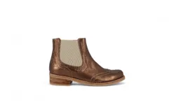 Botín tipo Chelsea de cuero metalizado en tono bronce, con paneles elásticos laterales en color beige. Presenta detalles de costuras decorativas tipo brogue en la puntera y laterales, con suela de goma antideslizante y taco bajo foliado.