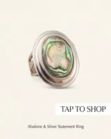 Anillo de plata con diseño ovalado que presenta una incrustación central de piedra abulón con reflejos iridiscentes.