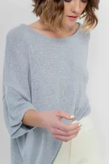 Sweater oversize de tejido liviano color blanco roto, con textura semi traslúcida, escote redondo y mangas amplias estilo murciélago.