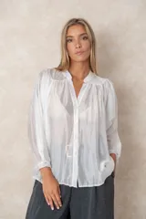 Camisa de organza blanca con cuello mao, diseño de manga larga tipo murciélago y cierre frontal con botones. Presenta un corte holgado y fluido.