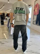 Remera gris de manga corta con estampa frontal y en la espalda con la frase "Stay Strong" y texto descriptivo de la marca Duxon Originals.