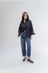 Camisa clásica de algodón con cuello camisero, cierre frontal de botones y mangas largas con puños anchos. Presenta un corte holgado y diseño minimalista.