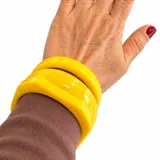 Conjunto de tres pulseras rígidas de resina en color amarillo, de diseño ancho y acabado brillante.