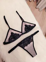 Conjunto de lencería compuesto por un corpiño triangular y una tanga regulable. Está confeccionado en microtul color tostado con detalles de encaje negro en los bordes y en las copas.