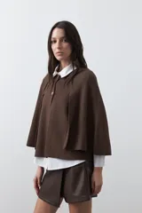 Saco tipo capa de punto color negro, con silueta fluida, corte amplio y cierre frontal con dos botones dorados.