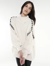 Sweater blanco de tejido grueso con cuello alto y mangas largas con detalle de costuras negras entrecruzadas en los hombros.
