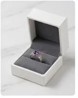 Anillo de plata 925 con piedra amatista central en corte cabujón, rodeada por un detalle de filigrana y diseño calado en los laterales del cuerpo.