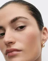 Aros tipo argolla gruesa, de metal dorado con diseño irregular.