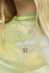 Collar doble de cadena fina bañado en plata de ley, con dos dijes colgantes en forma de mariposa de diferentes tamaños.