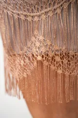 Vestido corto de encaje color beige con hilos dorados y flecos en el ruedo.