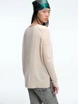 Sweater de tejido de punto color beige, con cuello redondo, manga larga y costura central vertical. Presenta un diseño con aberturas laterales en el ruedo y terminaciones acanaladas en puños y cuello.