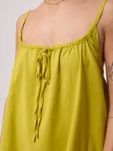 Vestido corto fucsia de algodón y lino, con breteles finos y escote recto con lazo ajustable.