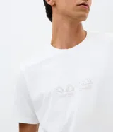 Remera masculina Blue Steel, de color blanco y corte regular. Con cuello redondo, mangas cortas y una estampa localizada minimalista en el pecho con iconos de viaje y la inscripción "PACK, HIKE, CAMP, REFLECT".