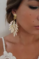 Aros colgantes con base dorada y múltiples piezas alargadas color crema.