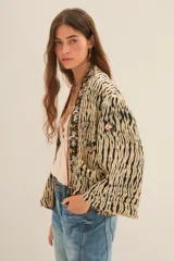 Kimono de corte holgado con estampado animal print tipo tigre, con bordes frontales decorados con pedrería y bordados artesanales. Presenta mangas anchas y forro interior.