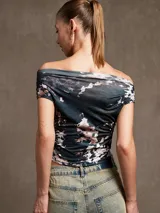 Top negro de manga corta con escote Bardot (hombros descubiertos) y detalle de drapeado o fruncido que termina en punta en el centro inferior.