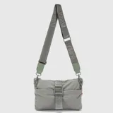 Cartera tipo bandolera de diseño minimalista y funcional, confeccionada en material sintético ligero de color gris. Cuenta con una correa ajustable con el logo de la marca estampado, cierre principal y un detalle de hebilla frontal con cinta decorativa.