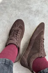 Championes de gamuza color tostado con diseño de paneles perforados en los laterales y empeine. Presentan cierre con cordones al tono y tirador en el talón.