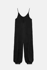 Mono de mujer color marrón oscuro, con escote redondo y tirantes finos. El tejido es satinado y plisado verticalmente. El pantalón es estilo bombacho con bajo abullonado ajustado con botón.