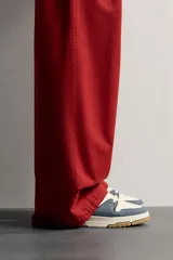 Zapatilla de básquet con cordones, diseño urbano de caña baja. Parte superior confeccionada en combinación de cuero sintético blanco y piezas de denim azul, con suela chunky de goma marrón y entresuela blanca.