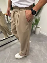 Pantalón sastrero de corte recto y holgado, color beige, con pinzas frontales y bolsillos laterales.