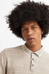 Sweater de punto color beige con cuello polo blanco y mangas largas.