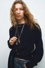 Pack de tres collares de estilo bohemio. Incluye un collar de cordón oscuro con nudos y dijes metálicos, un collar de eslabones metálicos con dijes variados y piedra de resina, y un collar doble de cadenas metálicas con dije de piedra engarzada en resina.