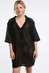 Vestido corto de tejido calado en color negro, con cuello polo, cierre frontal parcial con botones y mangas cortas. Presenta un diseño holgado y textura abierta.