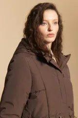 Campera acolchada de nylon en color crema, con capucha ajustable, cierre frontal con botones y cordón de ajuste en la cintura.