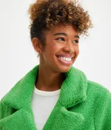 Campera alargada de sherpa color verde manzana, con cuello solapa, cierre cruzado con botones y bolsillos delanteros.