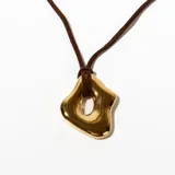 Collar con colgante dorado de forma orgánica y cordón marrón.