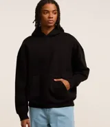 Hoodie cerrado negro, de corte boxy, con capucha, bolsillo canguro y puños ajustados.