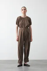 Pantalón baggy negro de silueta relajada con volumen amplio y caída fluida. Presenta detalles de ajuste con hebillas metálicas en el bajo y un cinturón de tela con hebilla metálica en la cintura.