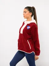 Buzo de micropolar color bordó con capucha, cierre frontal parcial y detalles en color crema. Presenta el logo de Umbro y el escudo del Club Nacional de Football bordados en el frente.