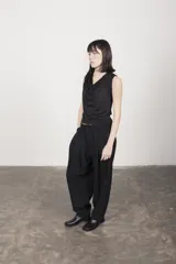 Pantalón de vestir negro, de corte amplio, con pliegues delanteros, bolsillos laterales y traseros.