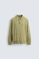 Polo de punto con diseño desagujado, color verde, de corte relajado, manga larga y cuello solapa con cierre frontal de tres botones. Presenta puños y ruedo con acabado en rib.