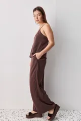 Pantalón wide leg de tiro medio y calce amplio, color marrón, con pinzas delanteras, cierre frontal y bolsillos laterales funcionales.