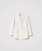 Blazer cruzado de lana color crudo, con solapas, cierre con botones a tono, manga larga con aberturas y bolsillos con solapa.