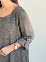 Sweater de punto color marrón chocolate, con escote redondo, mangas tres cuartos con trabilla y botón, y diseño holgado y acampanado.
